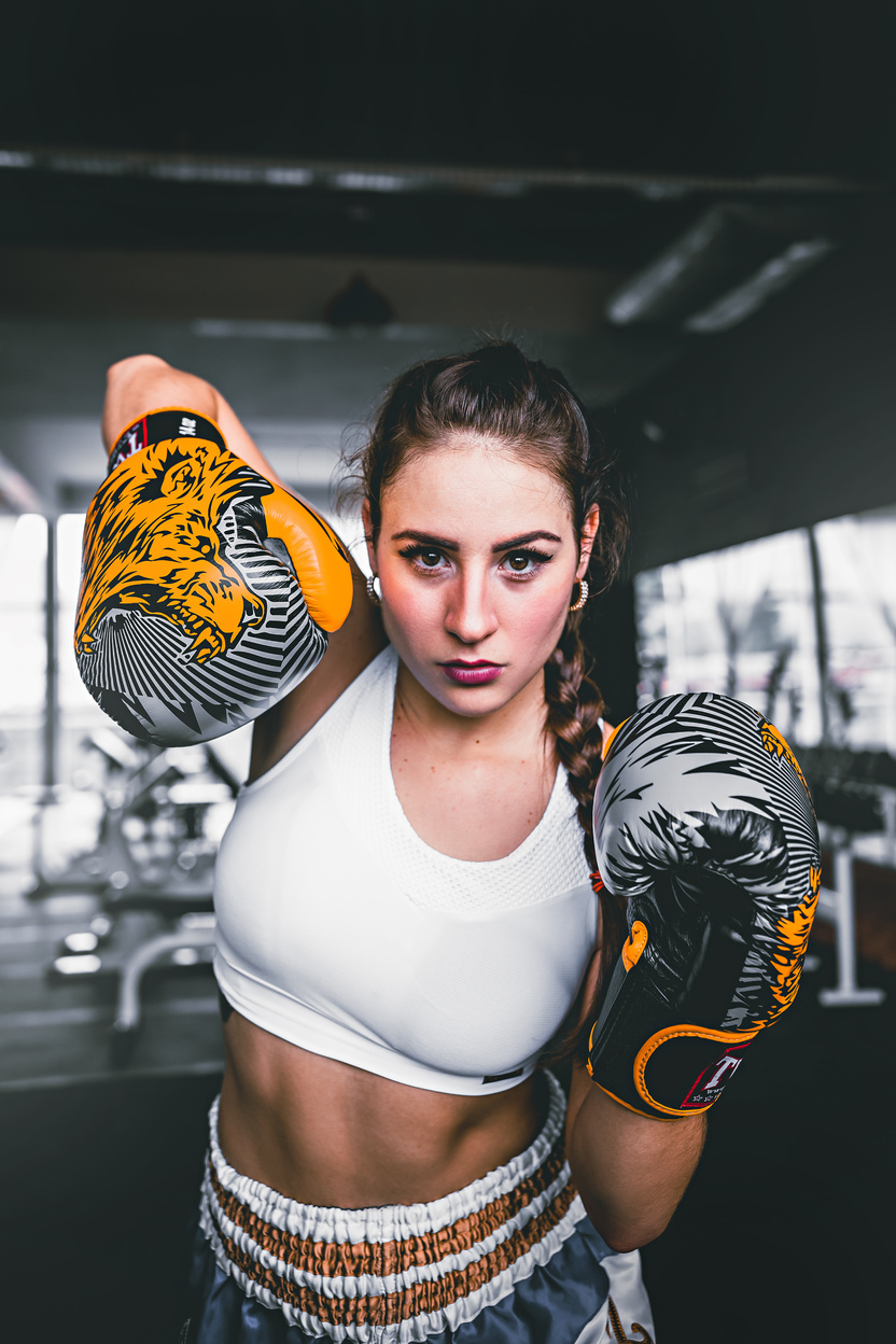 Confident strong woman showing bright boxing gloves